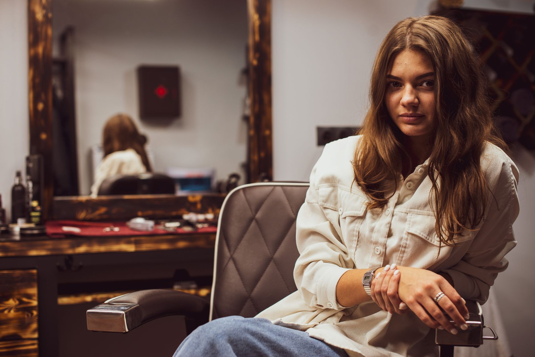Casual portrait of a woman sitting in a salon chair, reflecting in the mirror.