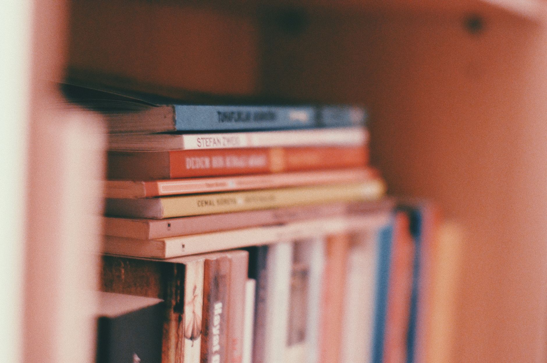 Closeup of stacked books on a wooden bookshelf, perfect for educational or literary themes.